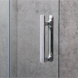 Chrome and matte black hinged shower door handle with white frame detail on concrete tile background, Flair ILI brand