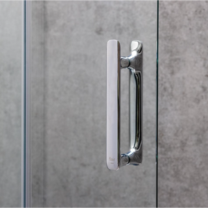 Chrome and white handle detail of Flair ILI bifold shower door against grey concrete wall tile background