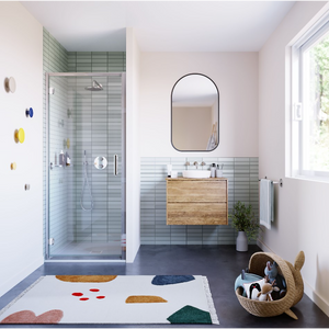 Modern bathroom featuring Flair ILI chrome hinge shower door with matte black frame, light blue horizontal tile walls, wooden vanity with white vessel sink, arched mirror, dark flooring, pink walls, and geometric patterned bath mat