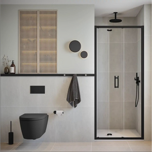 Modern bathroom featuring Flair ILI matt black bifold shower door with chrome frame, 800mm width, installed in minimalist space with white subway tiles, black wall-mounted toilet, rattan wall panels, ceiling mounted rainfall showerhead, and monochromatic décor