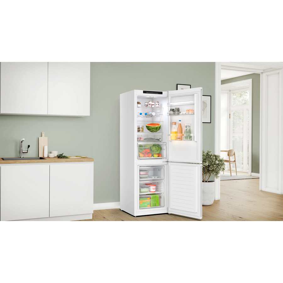 Bosch Series 4 white fridge freezer with open doors displaying fresh produce and groceries in a modern kitchen with sage green walls, white cabinetry and wooden worktops