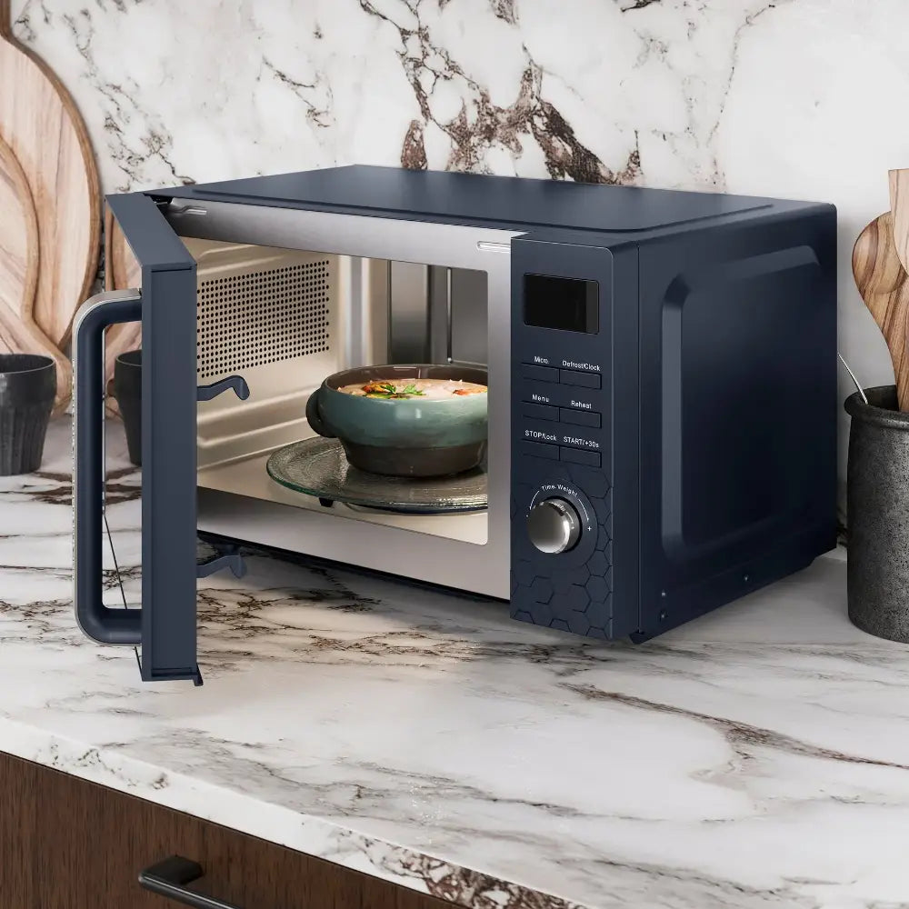 Morphy Richards Cassini Digital Microwave in black with 20 litre capacity, displayed on a marble countertop with door open showing a green bowl of food inside, featuring digital controls and a modern minimalist design