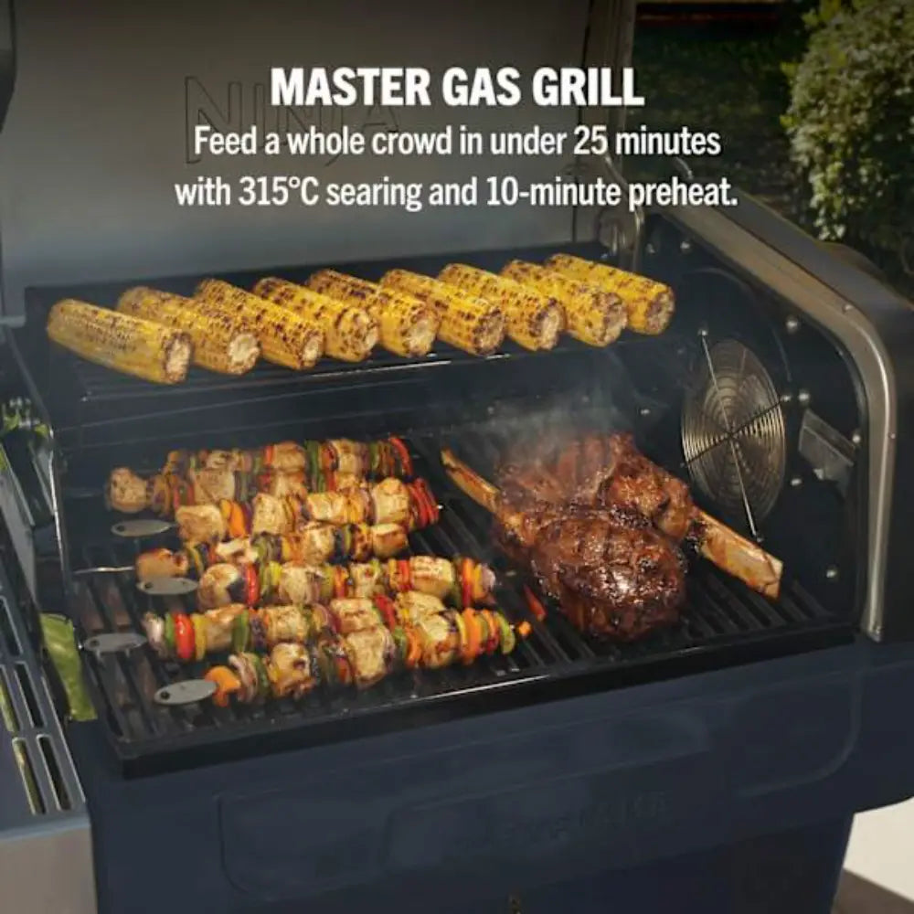 Ninja FlexFlame gas grill loaded with corn on the cob, vegetable skewers, and steaks cooking on multiple levels, demonstrating rapid cooking capacity for large groups