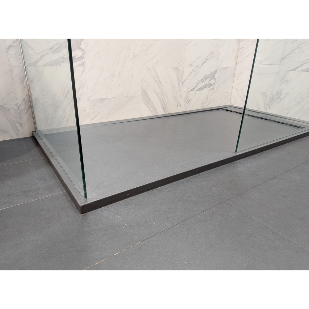 Modern rectangular shower tray in slate grey with 25mm height, installed in contemporary bathroom with marble-effect tile walls and black framed glass enclosure