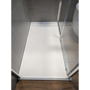 White rectangular shower tray with chrome frame and glass panel in modern bathroom with grey tile walls and wooden flooring