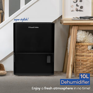 Russell Hobbs 10L black dehumidifier positioned on carpet next to wooden furniture in a modern home interior with "super stylish" text and product badge visible