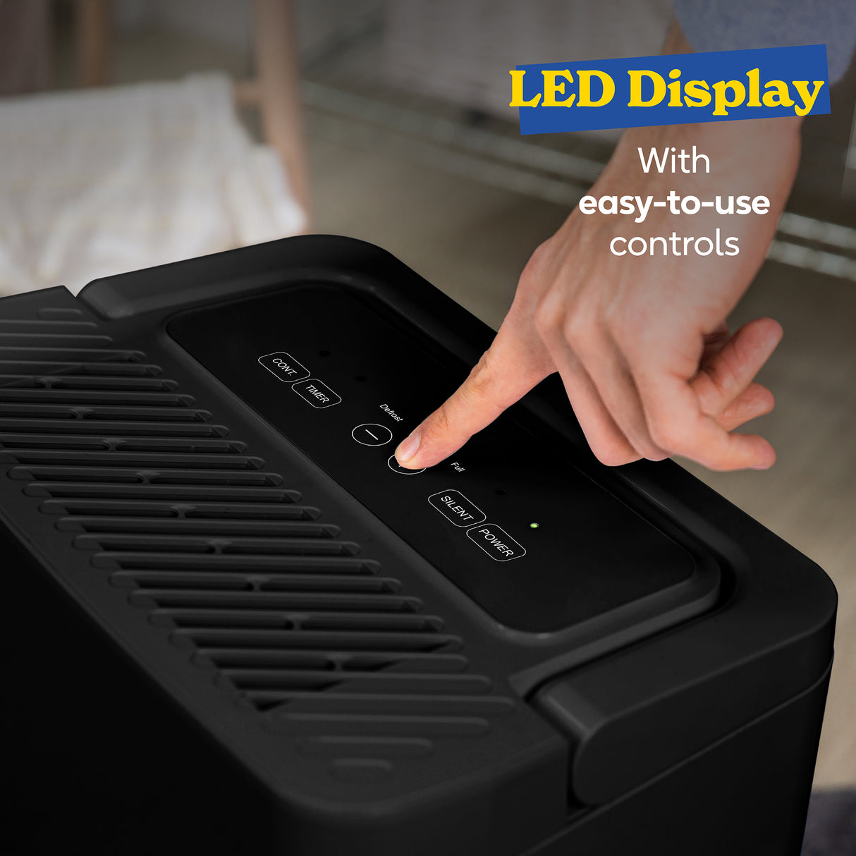 Close-up of hand operating LED display control panel on Russell Hobbs black dehumidifier with touch buttons for power, timer, and sleep mode settings