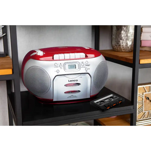 Red and white Lenco portable boombox with CD player and cassette deck on black shelf, featuring dual speakers, digital display, and control buttons with matching black cassette tape