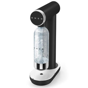 Smeg matte black and white sparkling water maker with CO2 bottle inserted, featuring circular control dial and chrome accents on white base