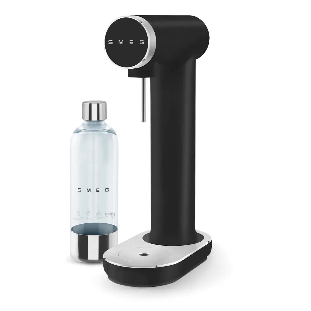 Smeg matte black sparkling water maker with cylindrical body, chrome circular control dial, white base, and clear glass bottle with stainless steel accents