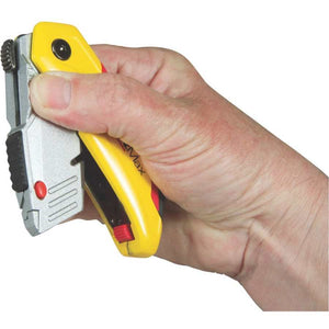 Hand holding Stanley Fatmax retractable folding knife with yellow and red handle, chrome blade housing, and red safety button against white background