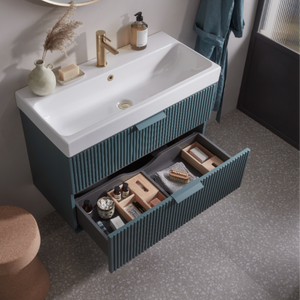 Roper Rhodes Scheme vanity unit in Derwent Blue with white ceramic basin, brass tap, and open drawers displaying storage organisation, modern bathroom furniture with ribbed cabinet design