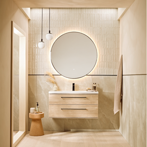 Modern bathroom vanity unit in sand oak finish with white ceramic sink, black tap, and round mirror mounted on beige tiled wall, featuring pendant lighting and minimalist design