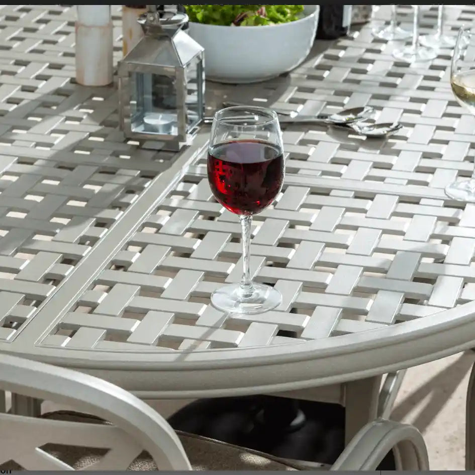 Hartman Berkeley cast aluminium garden furniture set with grey and white woven top table featuring red wine glass, white lantern, potted plant and cutlery in outdoor patio setting
