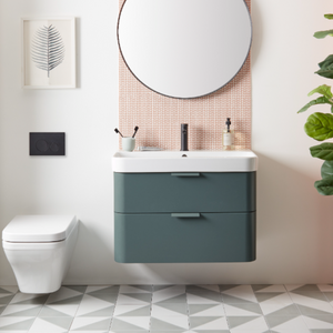 Modern bathroom with Derwent Blue wall-mounted vanity unit featuring white sink, round mirror with metal frame, pink mosaic tile backsplash, white toilet, geometric floor tiles, potted plants, and minimalist wall art