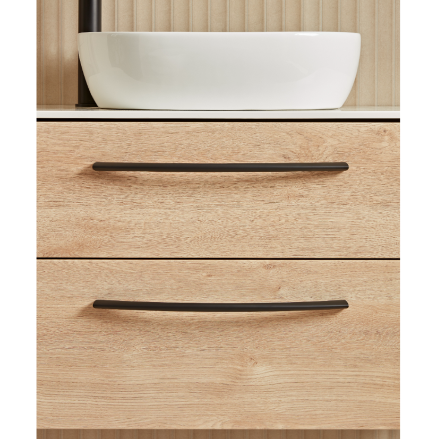 Sand Oak vanity unit with white ceramic countertop basin, two black handles, and wooden paneled backdrop in modern bathroom style