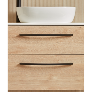 Sand Oak vanity unit with white ceramic countertop basin, two black handles, and wooden paneled backdrop in modern bathroom style