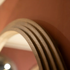 Close-up detail of natural wood frame showing stepped circular profile and grain texture of Tara Lane 90cm round wall mirror against terracotta background