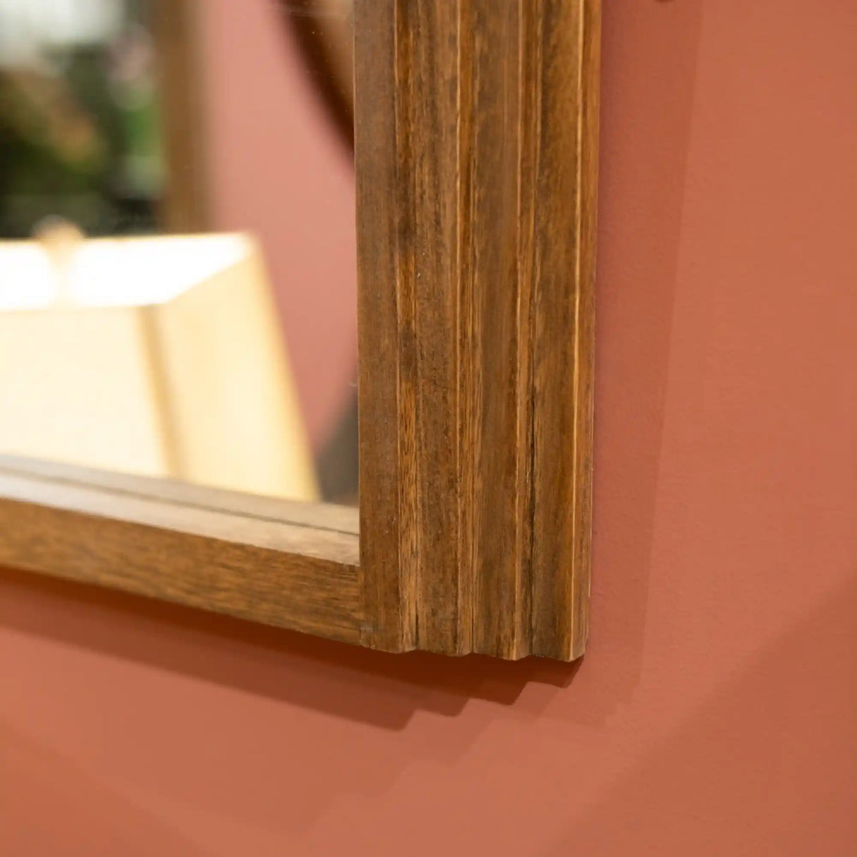 Tara Lane Stepped Arched Wall Mirror in natural wood frame against terracotta wall showing wooden frame detail and reflection
