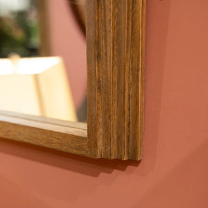 Tara Lane Stepped Arched Wall Mirror in natural wood frame against terracotta wall showing wooden frame detail and reflection