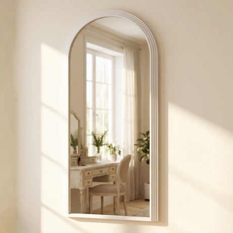 Tara Lane Arched Leaner Mirror in oyster white finish, 80cm x 180cm, leaning against cream wall with rounded top frame reflecting bright interior room with vanity desk and plants