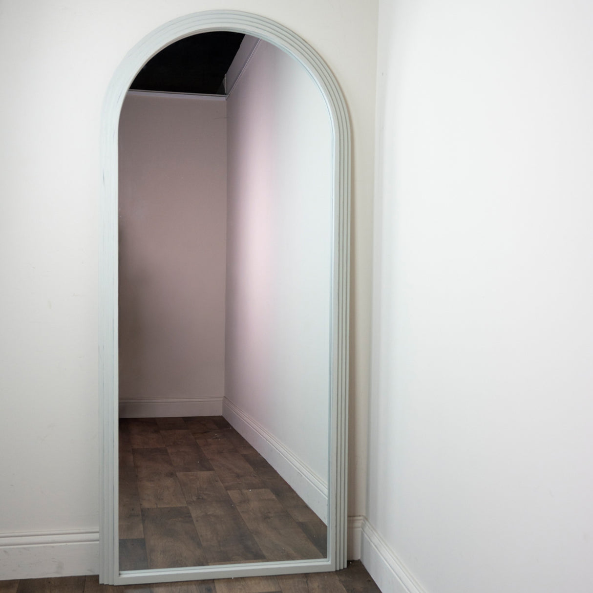Tara Lane Arched Leaner Mirror 80cm x 180cm in Oyster finish leaning against white wall showing tall arched frame with wooden flooring reflection
