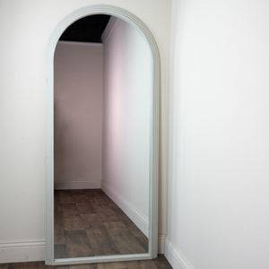 Tara Lane Arched Leaner Mirror 80cm x 180cm in Oyster finish leaning against white wall showing tall arched frame with wooden flooring reflection