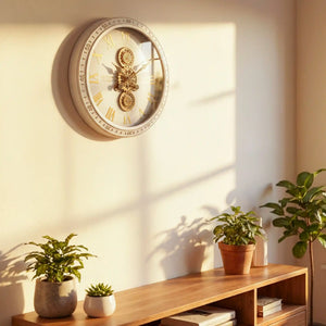 Tara Lane Old Town Gears Clock 50cm in ivory mounted on a cream wall above a wooden shelf with potted plants, featuring Roman numerals and visible brass gears mechanism in bright natural light