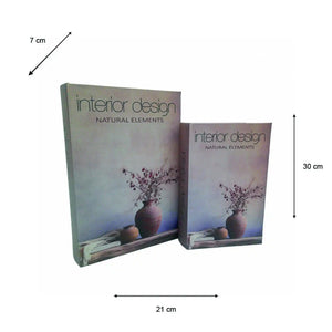 Two stacked Interior Design Natural Elements decorative book boxes with muted purple and blue gradient covers featuring a dark ceramic vase with dried flowers, measuring 21cm wide by 30cm tall, displayed with a 7cm diagonal scale reference