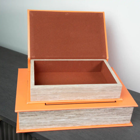 Two stacked decorative wooden book boxes with bright orange trim and natural wood sides, featuring terracotta-colored felt interiors, with the top box open to display storage space