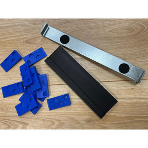Trojan Wooden Floor Fitting Kit comprising a grey canvas strap with metal buckle and black circles, a black storage box, and multiple blue plastic spacer wedges on wooden flooring
