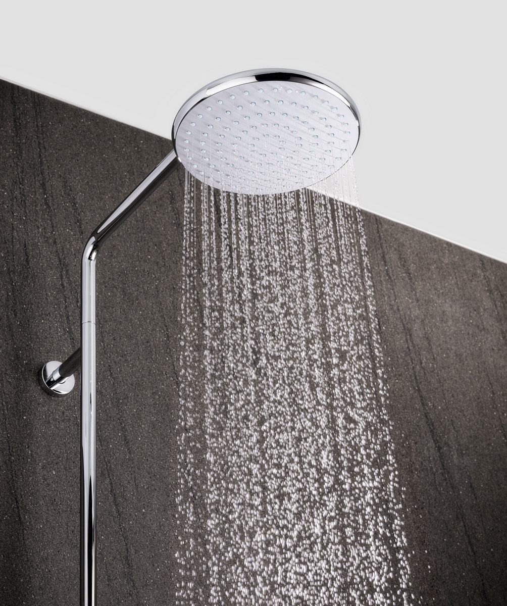 Chrome shower head with water stream on a gray background
