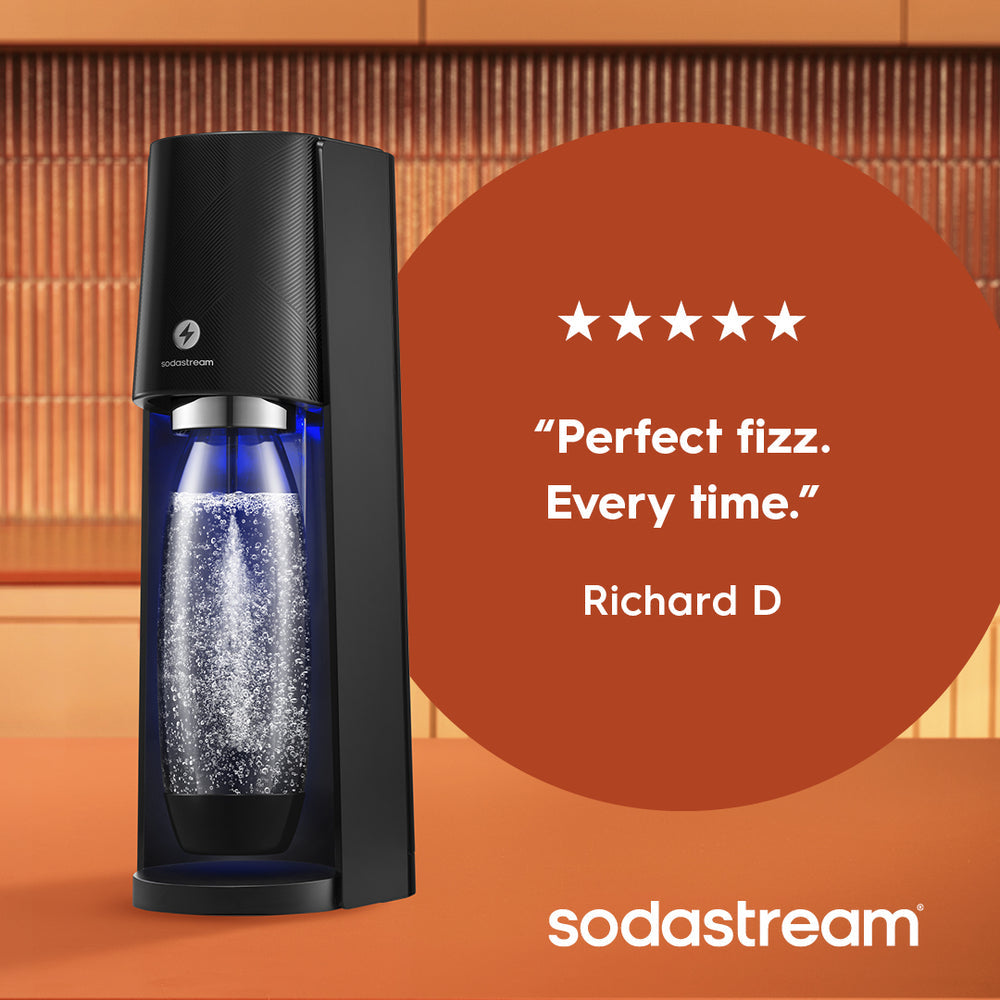 SodaStream E-Terra black sparkling water maker with blue water bottle filled with fizzy water, displayed against orange brick background with five-star customer review quote from Richard D stating "Perfect fizz. Every time"
