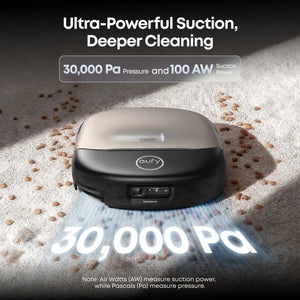 Eufy CleanMind AI robot vacuum in black and beige on light sand demonstrating 30000 Pa suction power with particles being pulled upward, highlighting ultra-powerful cleaning capabilities