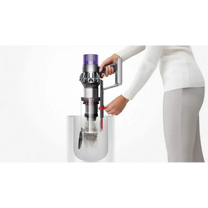 Person in white clothing demonstrating the Dyson Cyclone V10 Submarine wet and dry vacuum cleaner with purple top and silver metallic body being emptied into a white collection bin