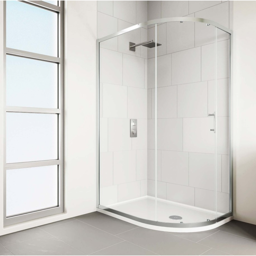 Modern chrome framed quadrant shower enclosure with curved glass doors and white acrylic tray, installed in white tiled bathroom with grey flooring next to large window