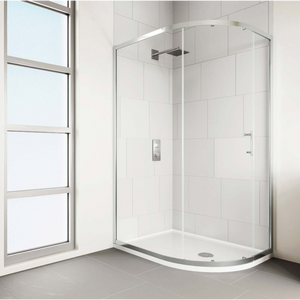 Modern chrome framed quadrant shower enclosure with curved glass doors and white acrylic tray, installed in white tiled bathroom with grey flooring next to large window