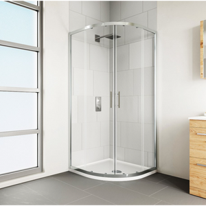 Chrome framed quadrant shower enclosure with curved glass doors and white tray base in modern bathroom with white subway tiles, grey flooring and wooden vanity unit