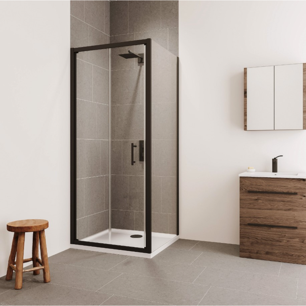 Modern bathroom interior featuring a Flair VERVE PRO bifold shower door with matt black frame and clear glass panels, positioned against grey tile walls with white base, accompanied by a wooden vanity unit with white sink, mirrored cabinet, wooden stool, and grey tiled flooring
