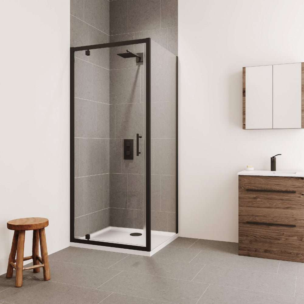 Modern bathroom interior featuring a black framed Flair Verve Pro pivot shower door with clear glass panels, gray tile walls and white base, alongside a wooden vanity unit with white sink, mirrored cabinet, and wooden stool on gray tile flooring