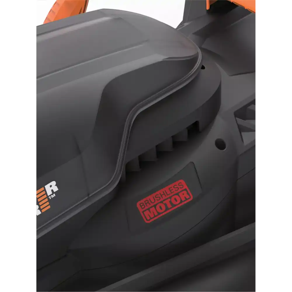 Close-up of WorX WG733E 20V cordless lawnmower showing black brushless motor housing with red brushless motor label, gray deck, and orange accents on the handle, viewed from the side detail perspective