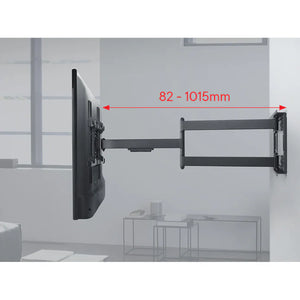 Black full motion TV wall bracket mount with articulating arm extended showing 82-1015mm extension range, mounted on white wall with grey structural elements in background
