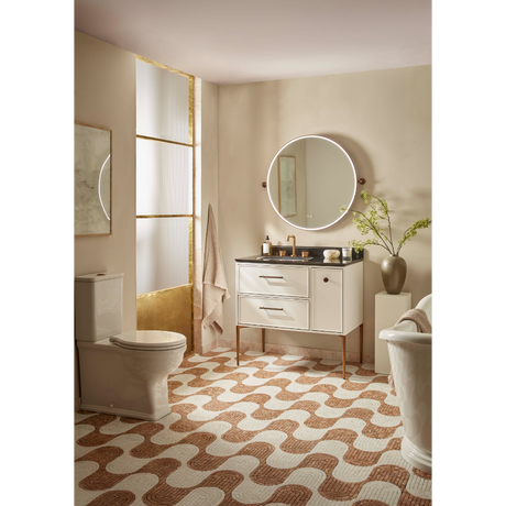 Modern bathroom featuring a Roper Rhodes Walcot 900mm vanity unit in matt white with light oak legs, paired with a circular illuminated mirror, chrome fixtures, and complementary freestanding bathtub in a neutral beige and terracotta geometric tiled floor setting