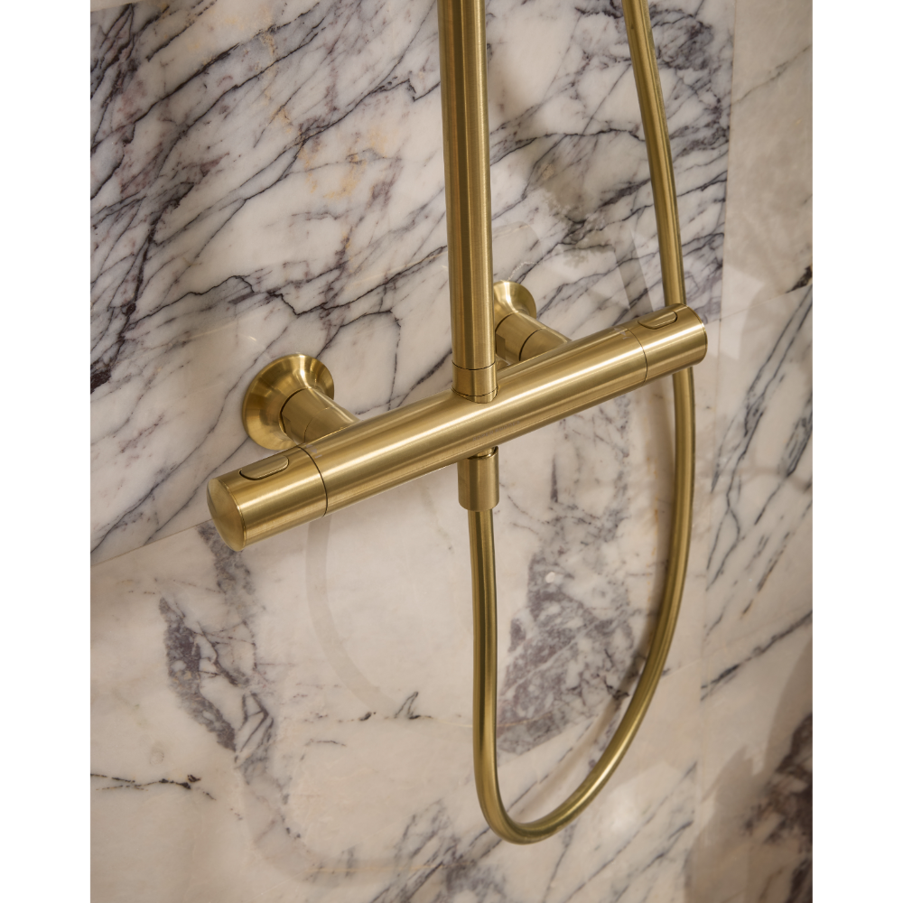 Brushed brass concealed shower system with bar mixer and sliding hand shower rail mounted on white marble wall with grey veining