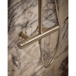 Close-up of Roper Rhodes Walcot concealed shower system in brushed nickel finish mounted on marble wall with horizontal bar and vertical rail against veined white and grey marble tiles