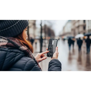 Person in winter clothing holding a smartphone displaying the Dyson Hot + Cool HF1 app interface on a blurred urban street