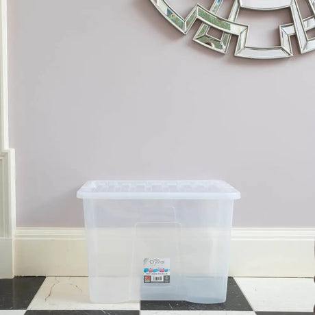 Clear plastic storage box with lid by Wham Crystal 80 litre capacity displayed on black and white marble floor against pale pink wall with white baseboards and decorative silver mirrors above