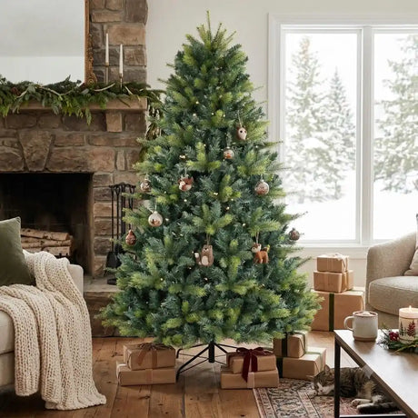 Puleo 7.5ft Kensington Fir artificial Christmas tree decorated with rose gold baubles and woodland ornaments in a cosy living room setting with stone fireplace, wrapped gifts, and snowy forest view through windows