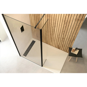 Modern bathroom wetroom setup featuring Flair AYO 8mm glass panels with matte black frame, cream tile flooring, wooden wall paneling, linear floor drain, and minimalist black side table with accessories