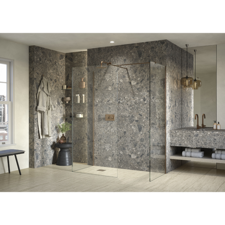 Modern luxury bathroom featuring Flair AYO 8mm glass wetroom panels with brushed brass hardware, grey marble-effect wall panels, light wood flooring, integrated shelving, pendant lighting, and a floating concrete sink vanity